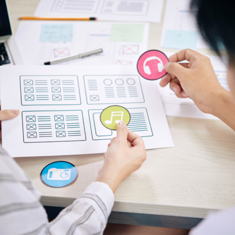 Coworkers choosing icons for new web app sitting at desk with papers