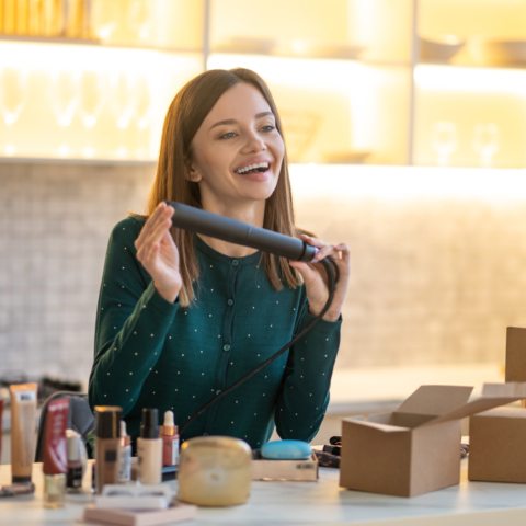 Hairdressing. Smiling young hairdresser holding hair straighntener and looking contented