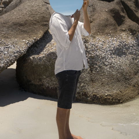 man-beach-posing-with-round-reflective-mirror